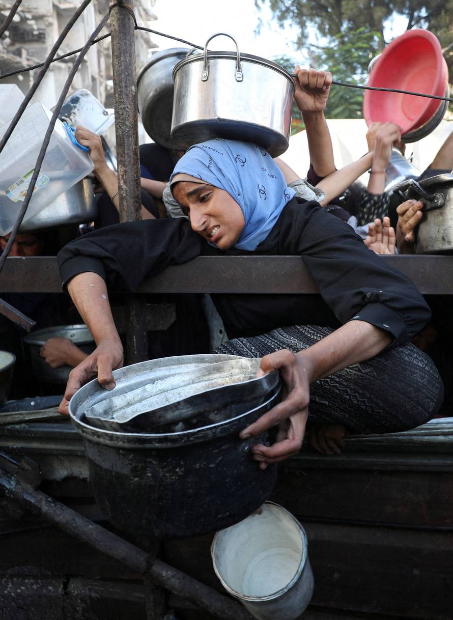 Palestinians wait to receive food from a charity kitchen, amid a hunger crisis, in Gaza City