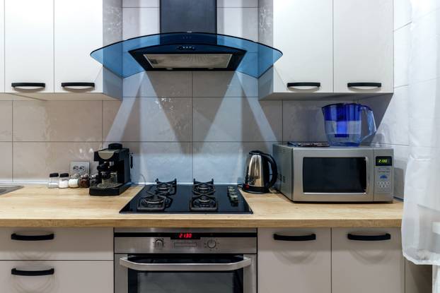 View of a modern kitchen with blue hood, kitchen appliances and dining table