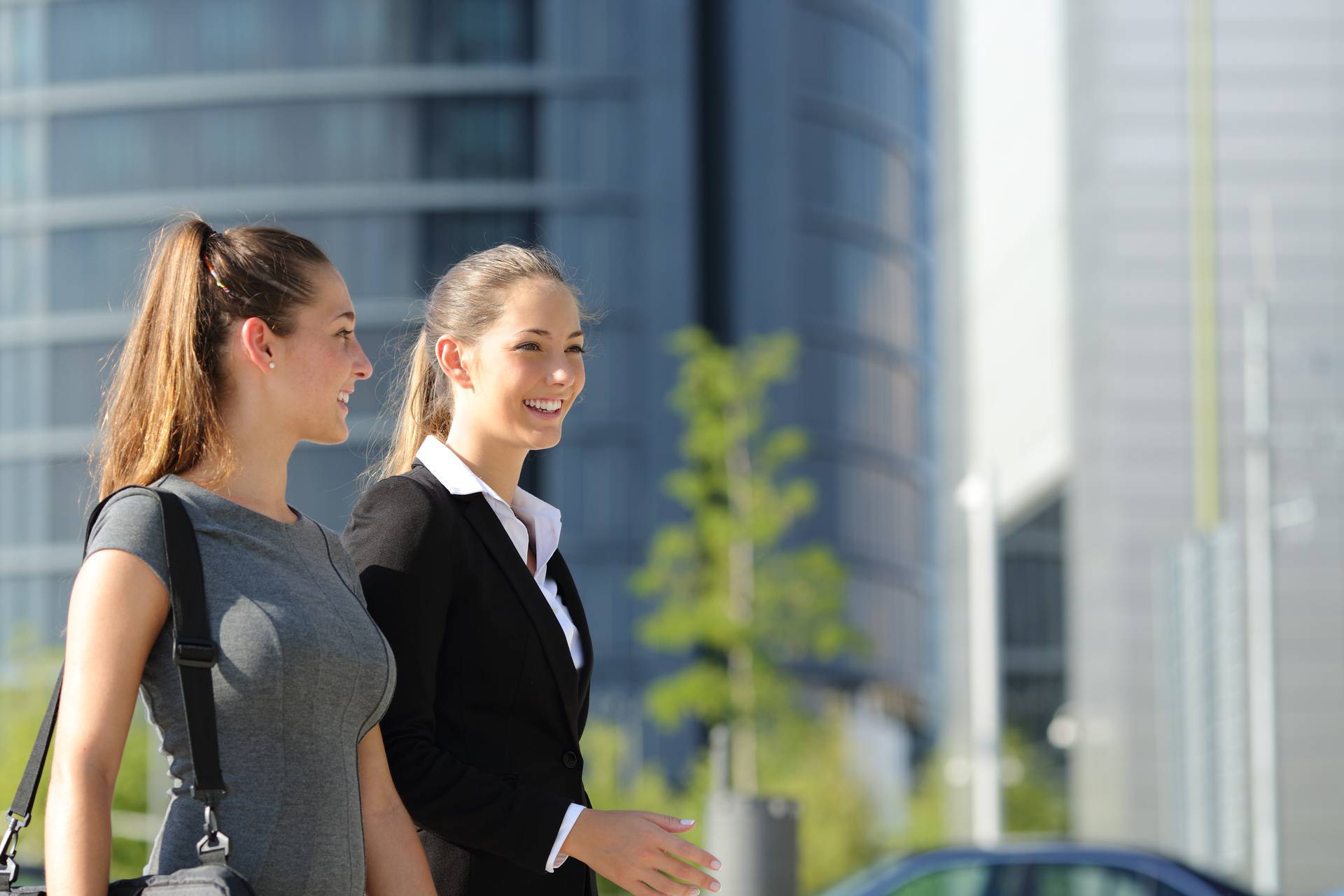 Two,Happy,Businesswomen,Walking,And,Talking,In,The,Street,With