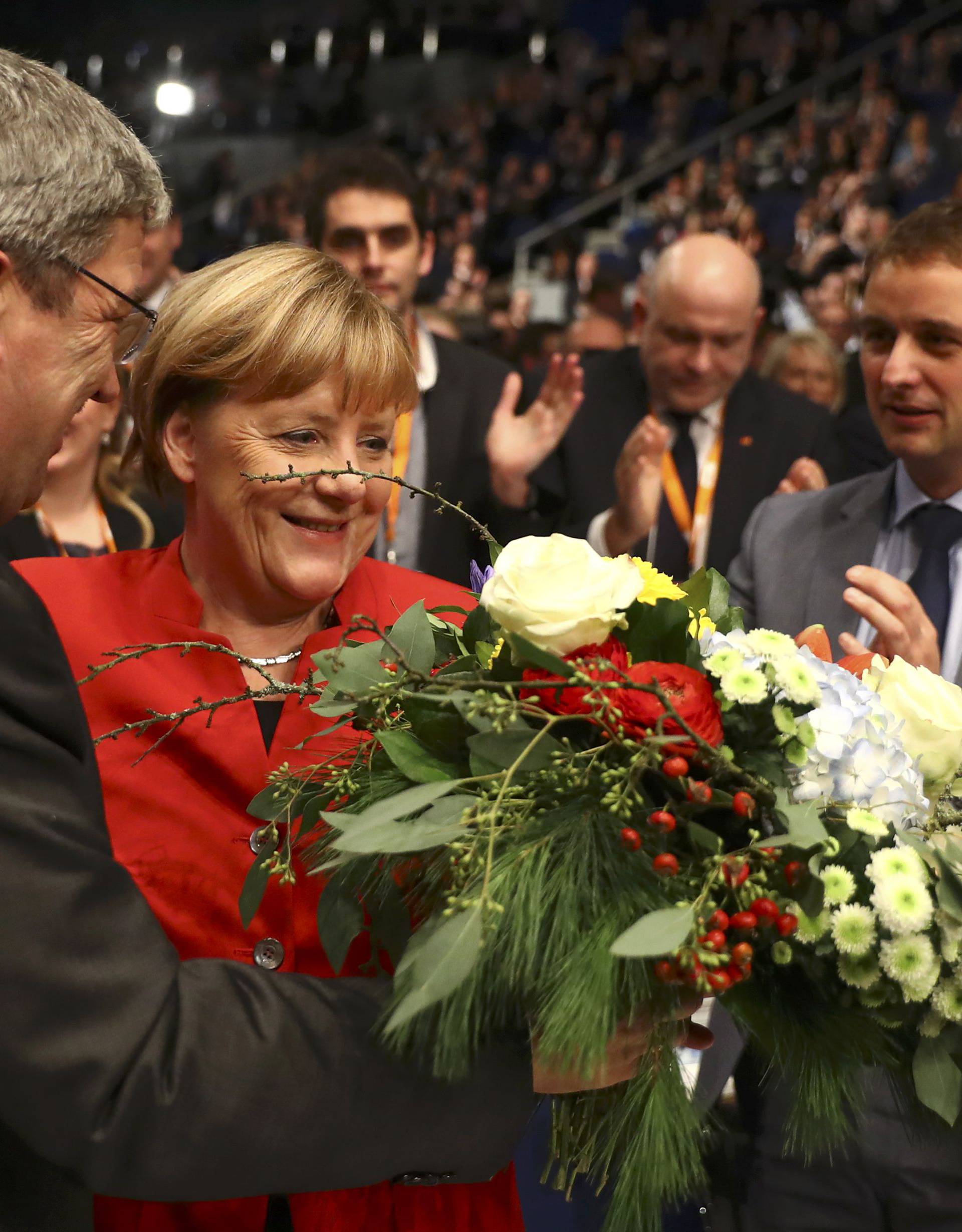 German Chancellor and leader of the conservative CDU Merkel receives flowers after she was re-elected as chairwoman at the CDU party convention in Essen