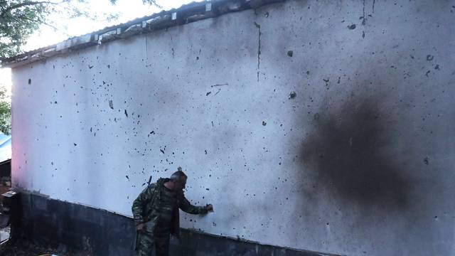 A man stands next to a building damaged by shelling in Jermuk