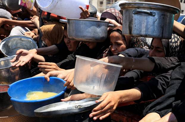 Palestinians wait to receive food from a charity kitchen, in Gaza City