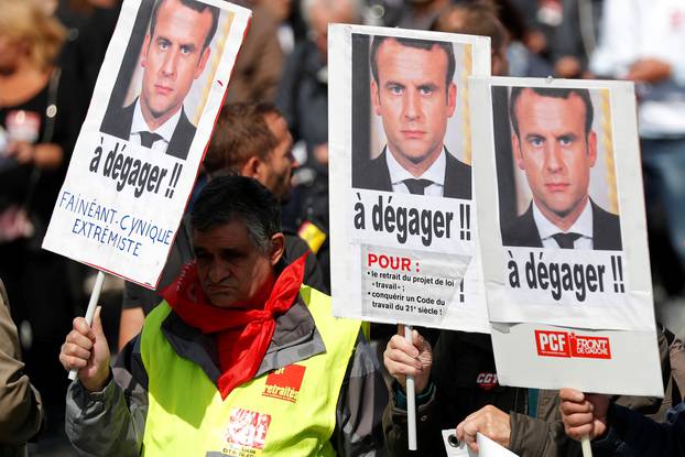 Demonstrators hold placards with portraits of French President Emmanuel Macron and the slogan "To clear out" during a national strike and protest against the government