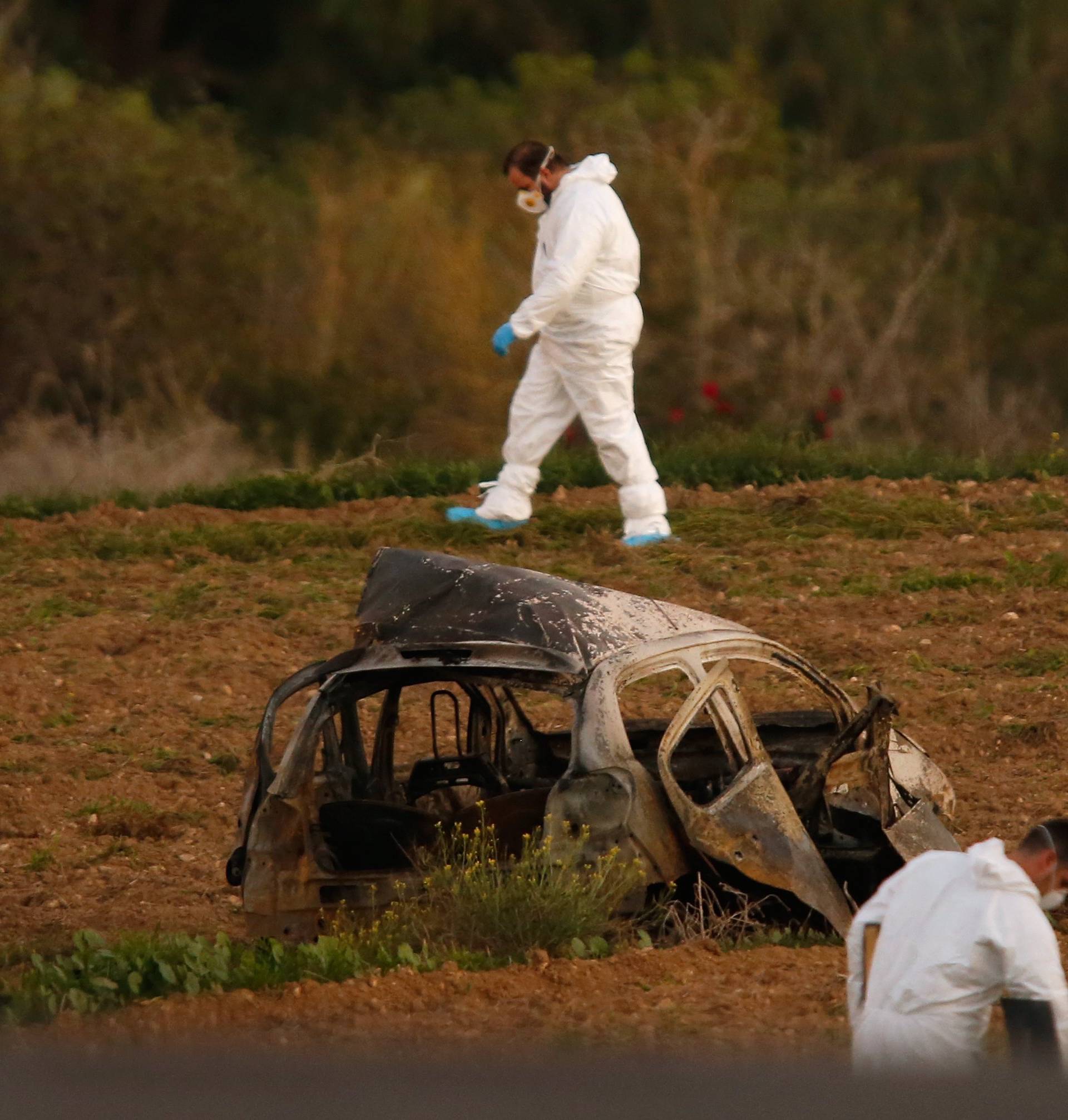 Forensic experts walk in a field after a powerful bomb blew up a car killing investigative journalist Daphne Caruana Galizia in Bidnija