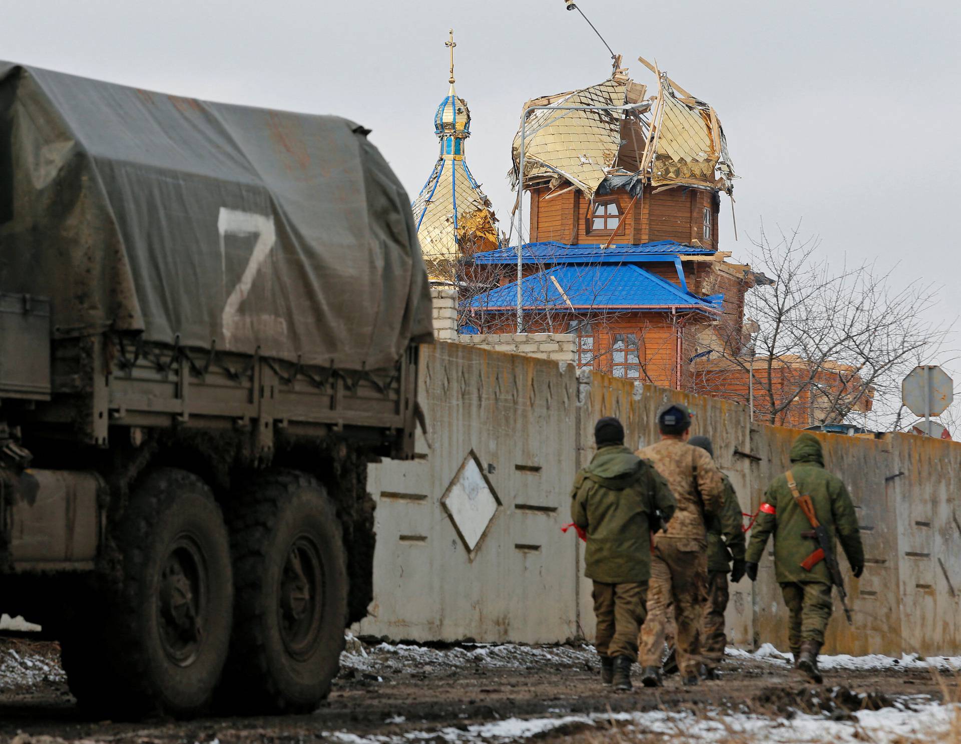 Service members of pro-Russian troops walk near a church which was damaged during Ukraine-Russia conflict in Volnovakha