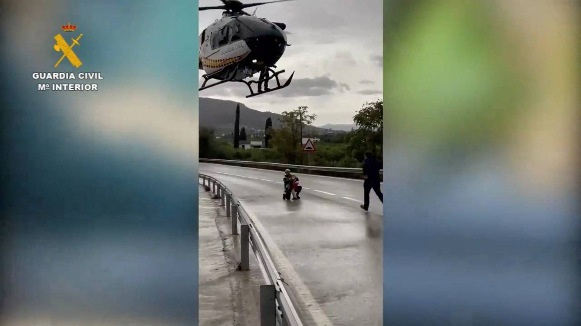 A member of the Spanish Civil Guard rescues a child who was trapped by floods