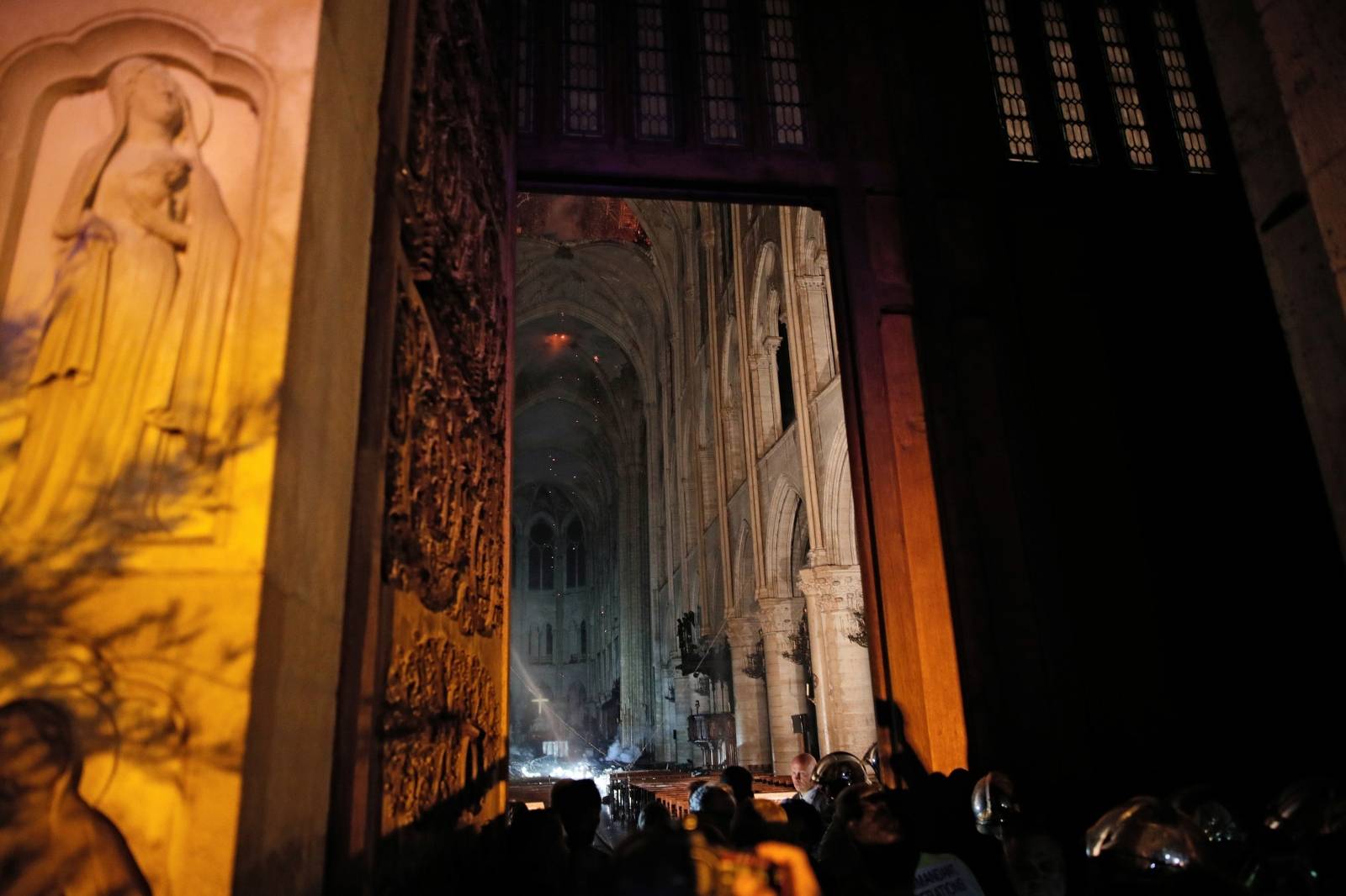 General view from the entrance shows smoke rising around the alter in front of the cross inside the Notre Dame Cathedral as a fire continues to burn in Paris