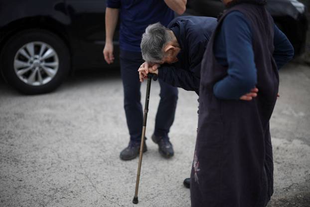 An elderly man rests on his cane as he reacts near a burnt church after a wildfire devastated the area, in Uiseong