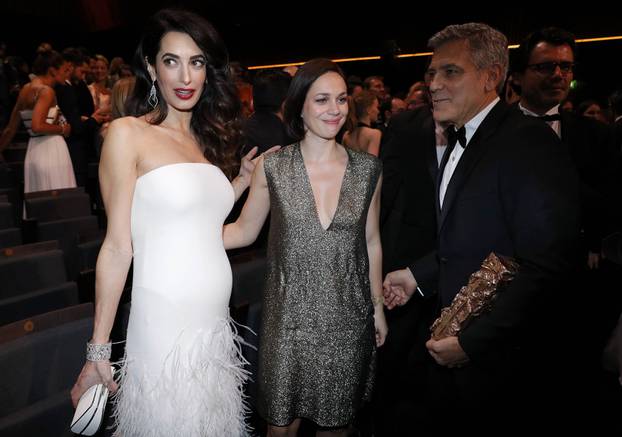 Actor George Clooney holds his Honorary Cesar Award as he leaves with his wife Amal and Nathalie Pechalat at the end of the 42nd Cesar Awards ceremony in Paris