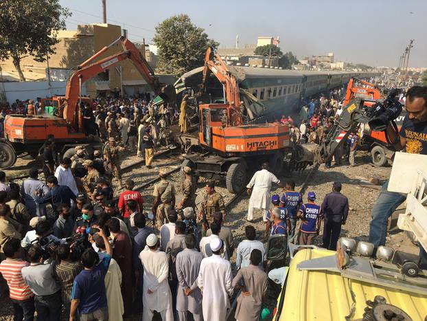 Rescuers workers use heavy machinery on the car of a train which crashed outside Karachi,