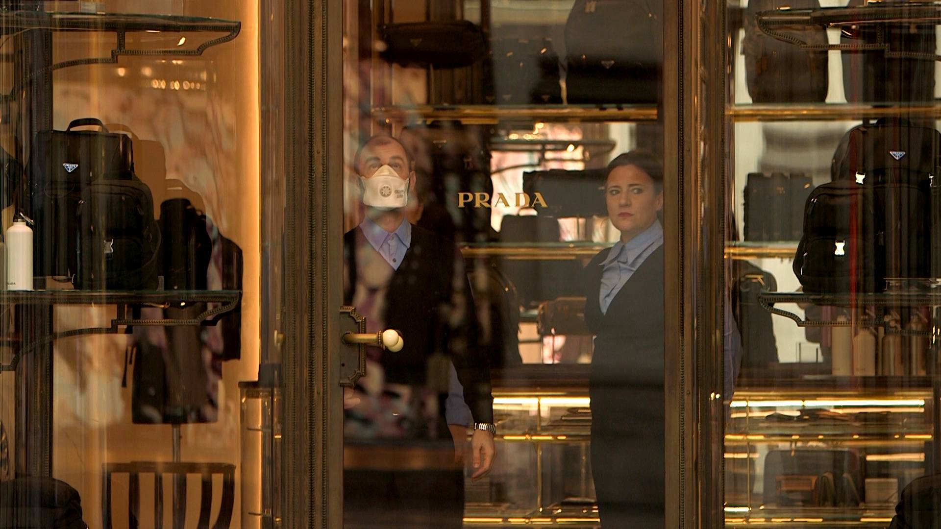 A shop assistant in a face mask looks on after the Italian government imposed a virtual lockdown on the north of the country, in Milan