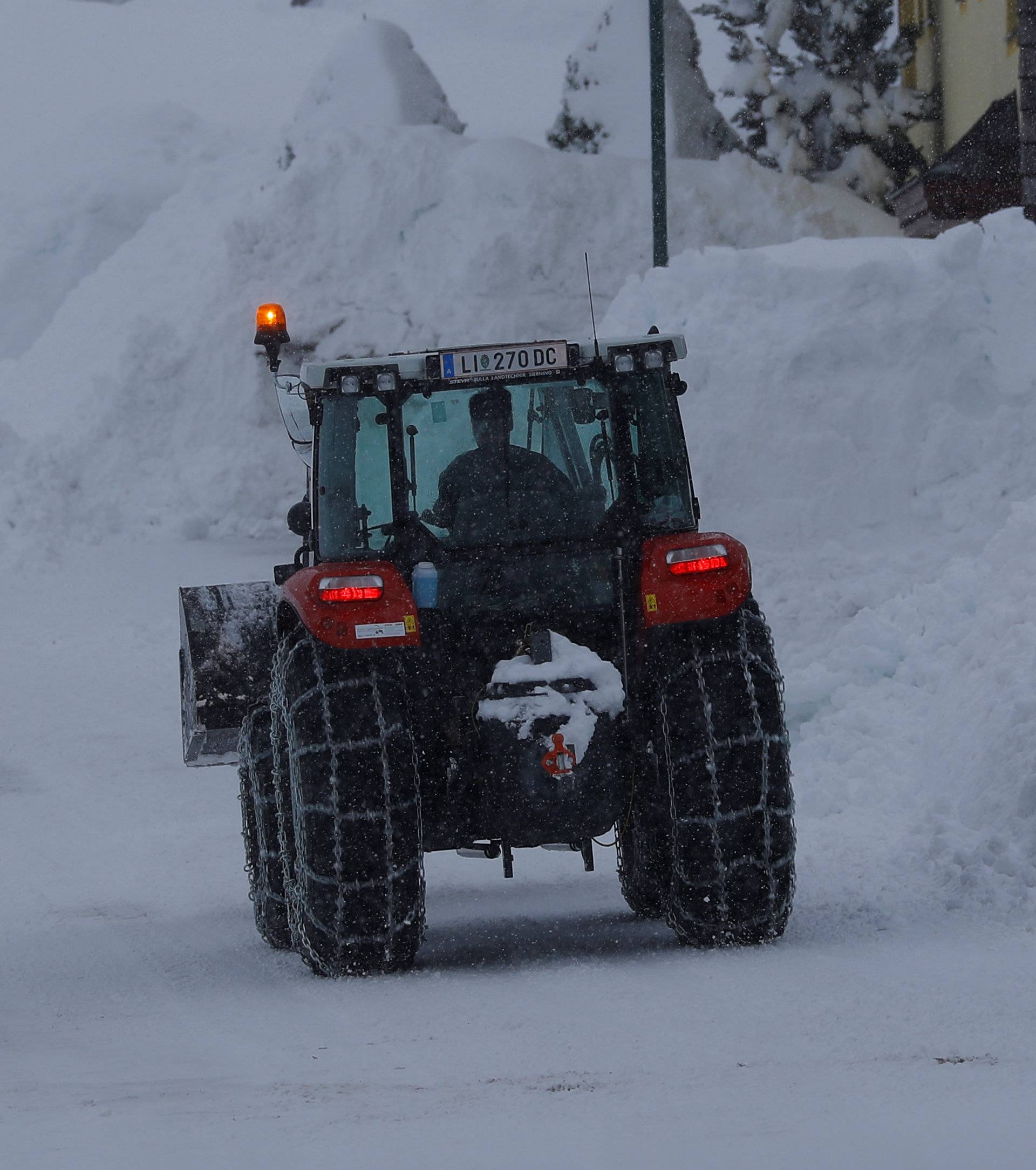 A tractor shovels snow on an icy road after heavy snowfall in Knoppen