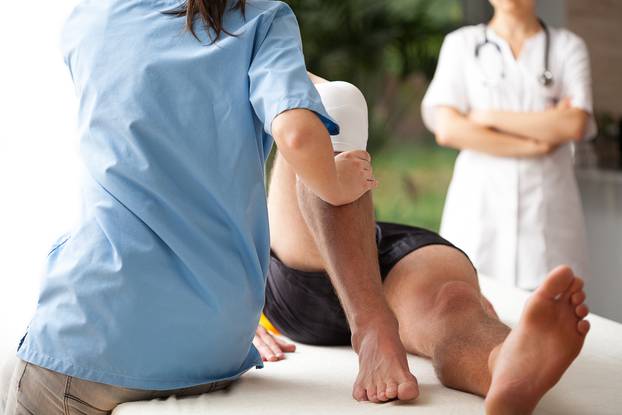 Female,Physiotherapist,Helping,To,Exercise,The,Patient,Injured,Knee