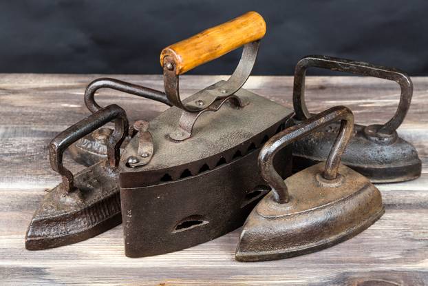 Vintage irons on wood table against dark background