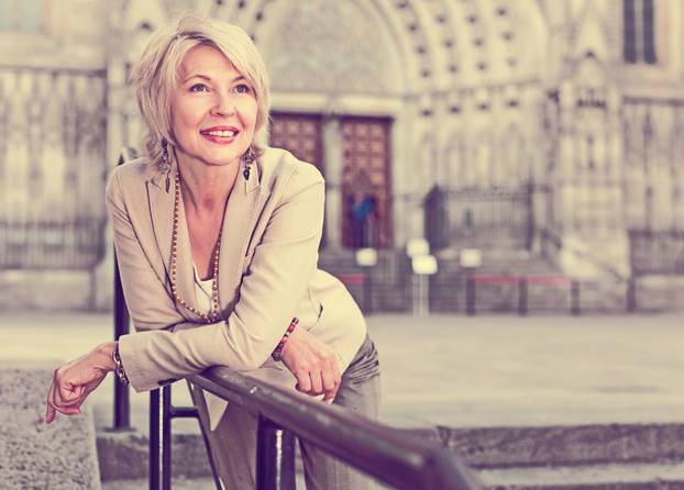 Cheerful mature female is walking in classic jacket