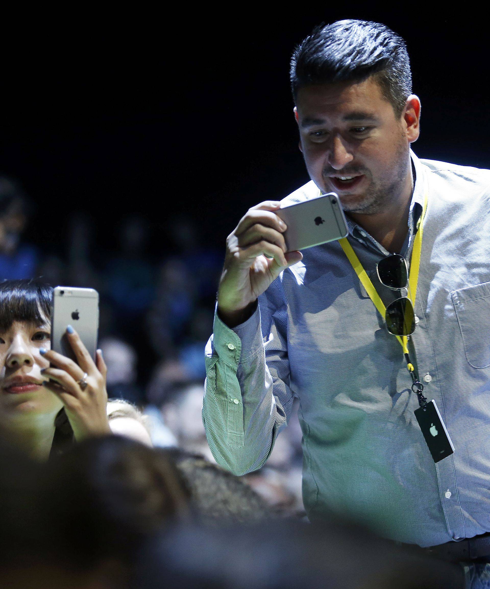 Attendees use their iPhones during an Apple media event in San Francisco