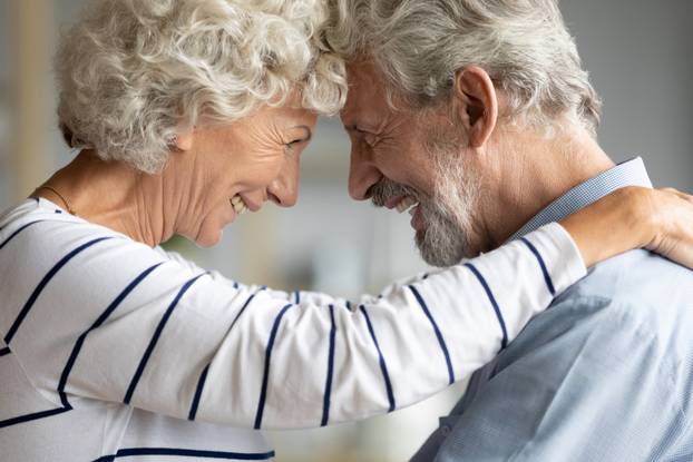 Aged couple looking at each other touching with foreheads