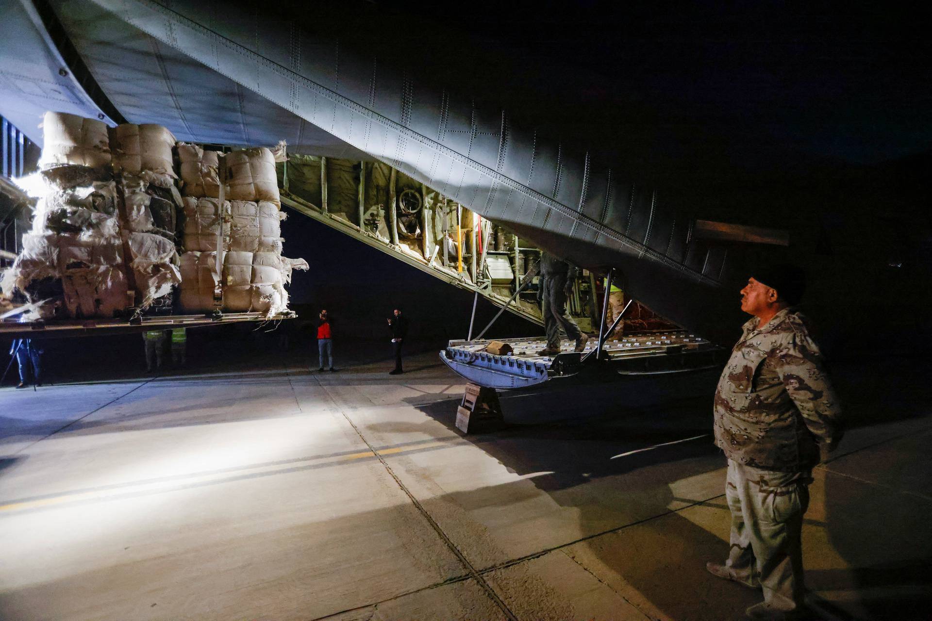 Workers and security forces process aid from Red Crescent that will be shipped on a plane of emergency relief to Syria to support victims of the deadly earthquake, at a military airbase near Baghdad International Airport, in Baghdad