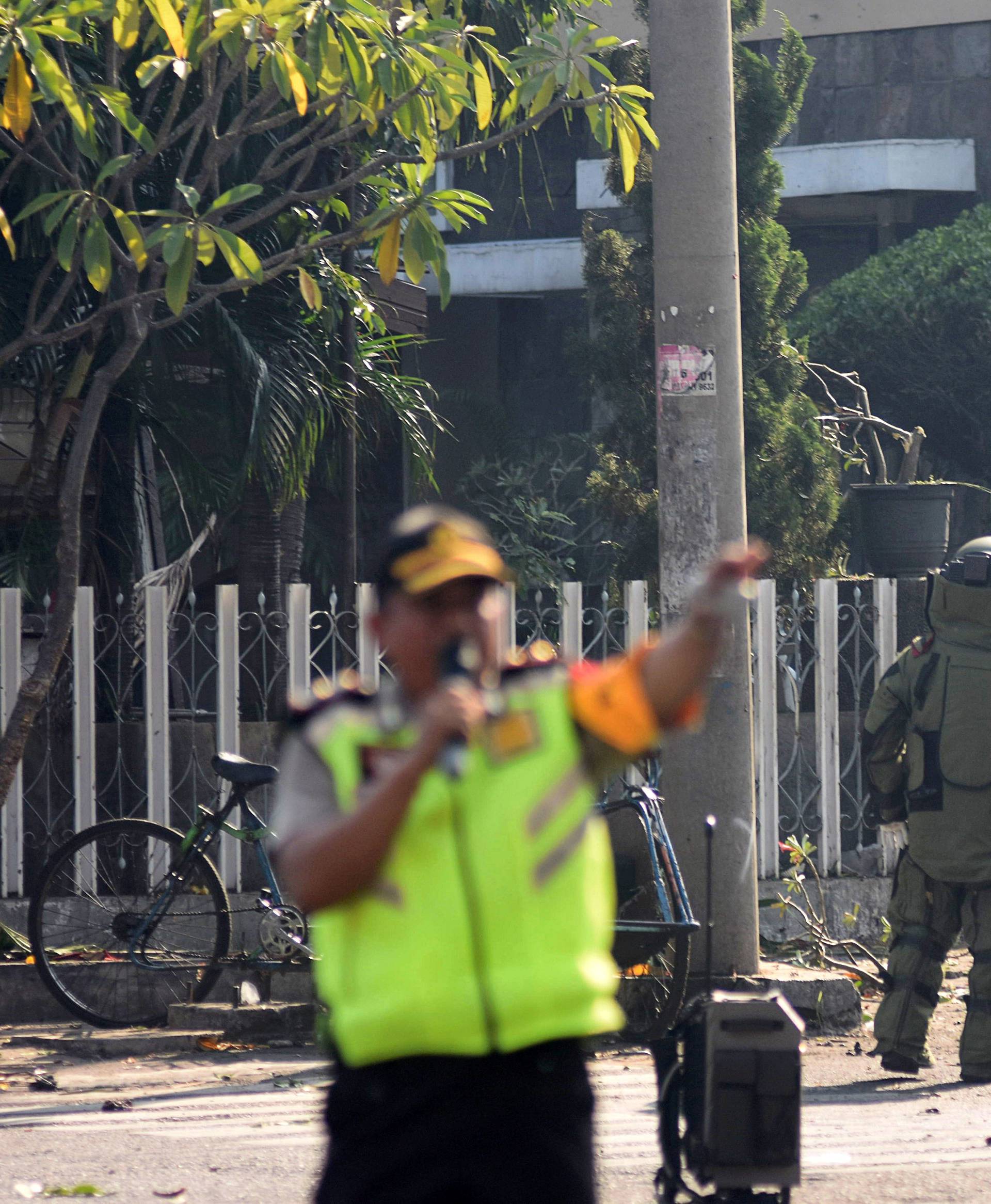A member of the police bomb squad unit examines the site of an explosion outside the Immaculate Santa Maria Catholic Church, in Surabaya, East Java