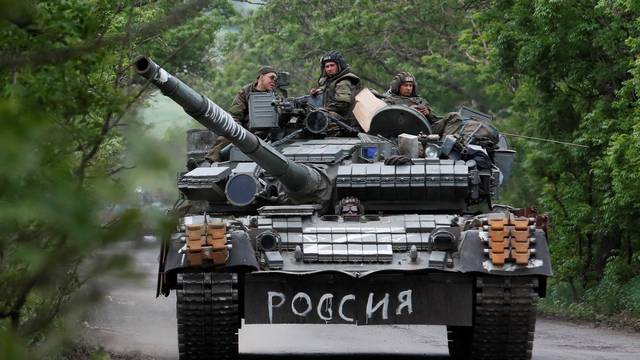 Service members of pro-Russian troops drive a tank in the Donetsk Region