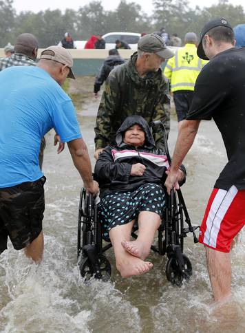 An elderly woman in a wheelchair is rescued from the flood waters of tropical storm Harvey in east Houston