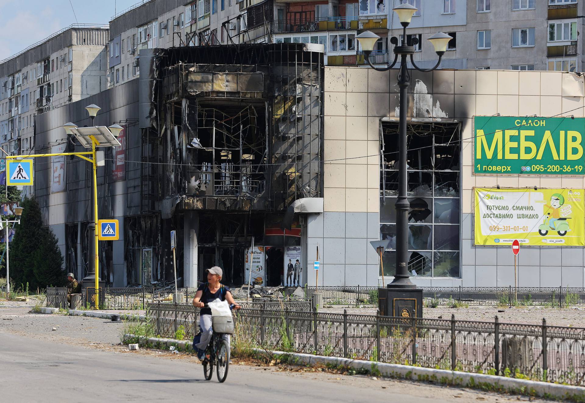 A local resident rides a bicycle past a damaged building in Lysychansk