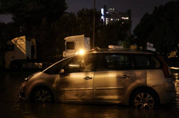 Demetrio, 75, sits inside his car while waiting for a tow truck after the vehicle became submerged in floodwater, on the outskirts of Barcelona