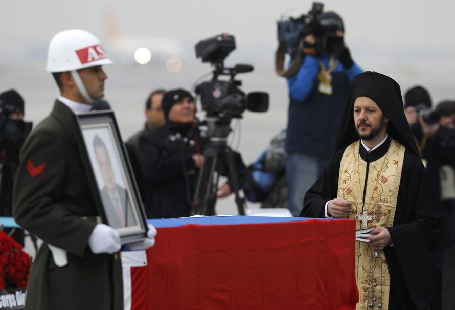 An ortodox clergyman prays next to flag-wrapped coffin of late Russian Ambassador to Turkey Karlov during a ceremony at Esenboga airport in Ankara