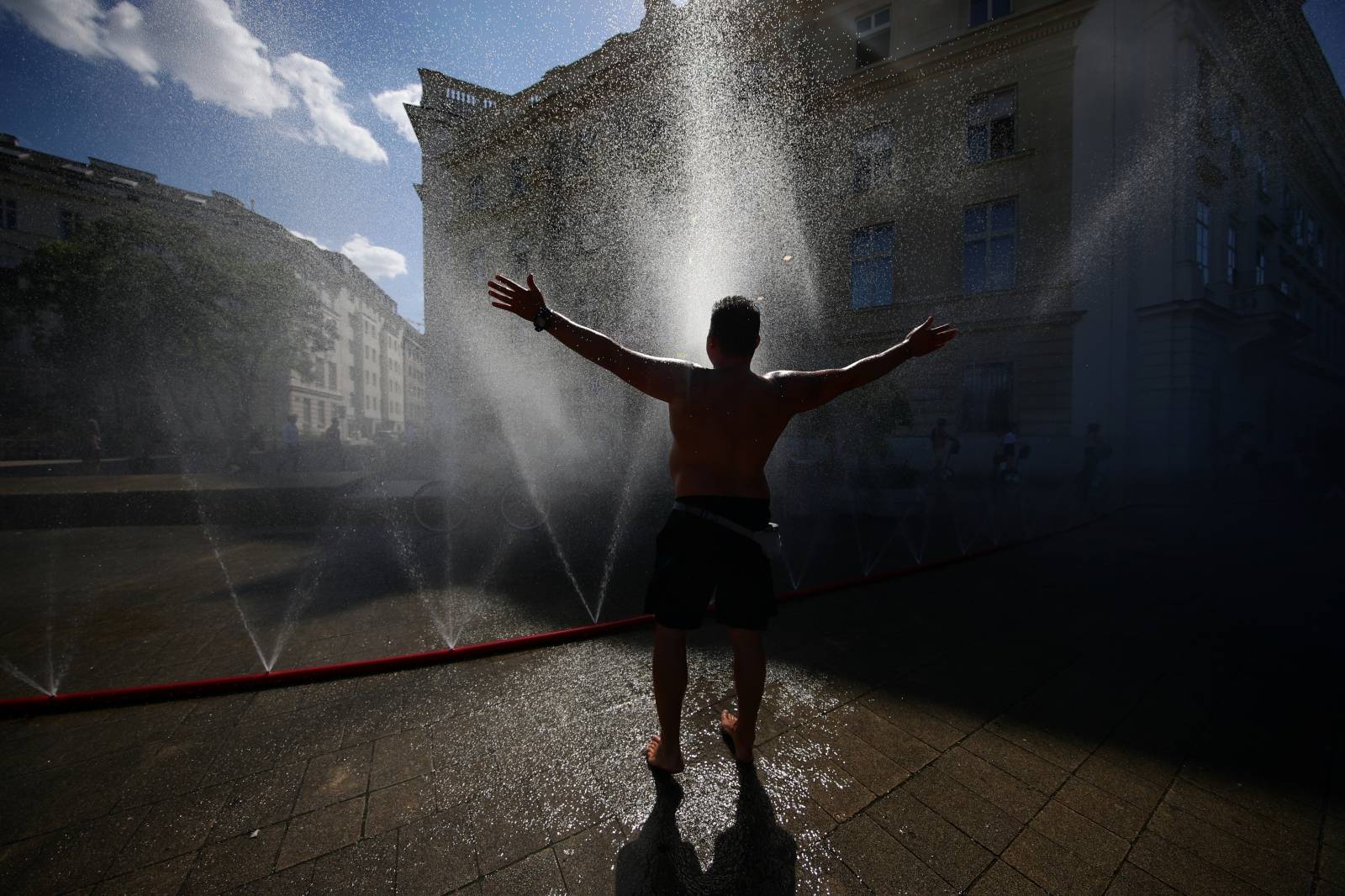 A man cools off under water sprinklers during a heat wave in Vienna