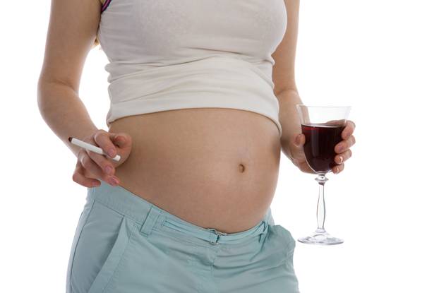 Pregnant woman holding wine and cigarette