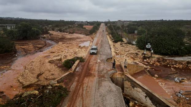 Aerial view of people standing in a damaged road as a powerful storm and heavy rainfall hit Shahhat city