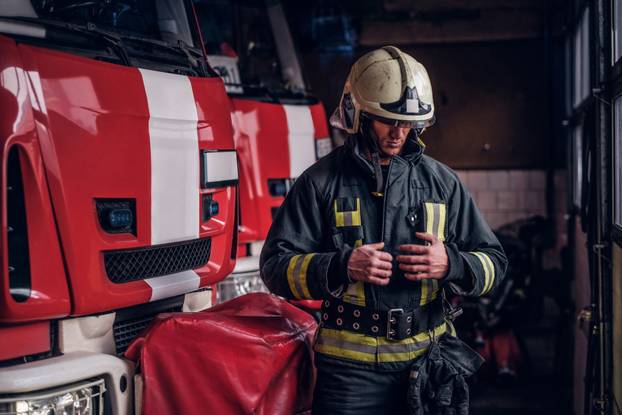 Fireman clothes protective uniforms standing next to the fire engine in the garage