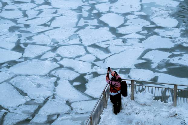 A pedestrian stops to take a photo by Chicago River as bitter cold phenomenon called the polar vortex has descended on much of the central and eastern United States