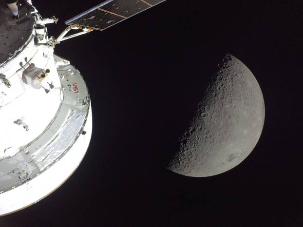 NASA’s Orion spacecraft is seen in the foreground, lit up by the Sun as a first quarter Moon is visible behind it