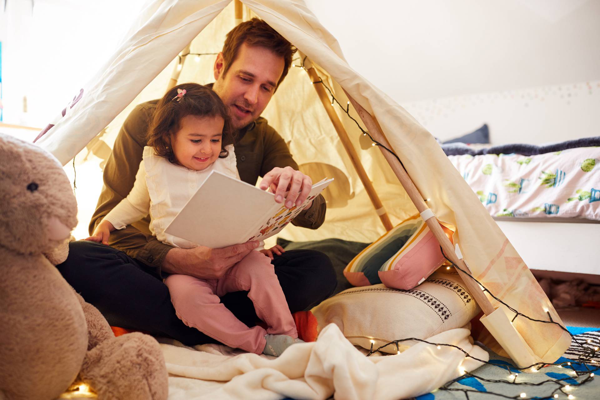 Single Father Reading With Daughter In Den In Bedroom At Home