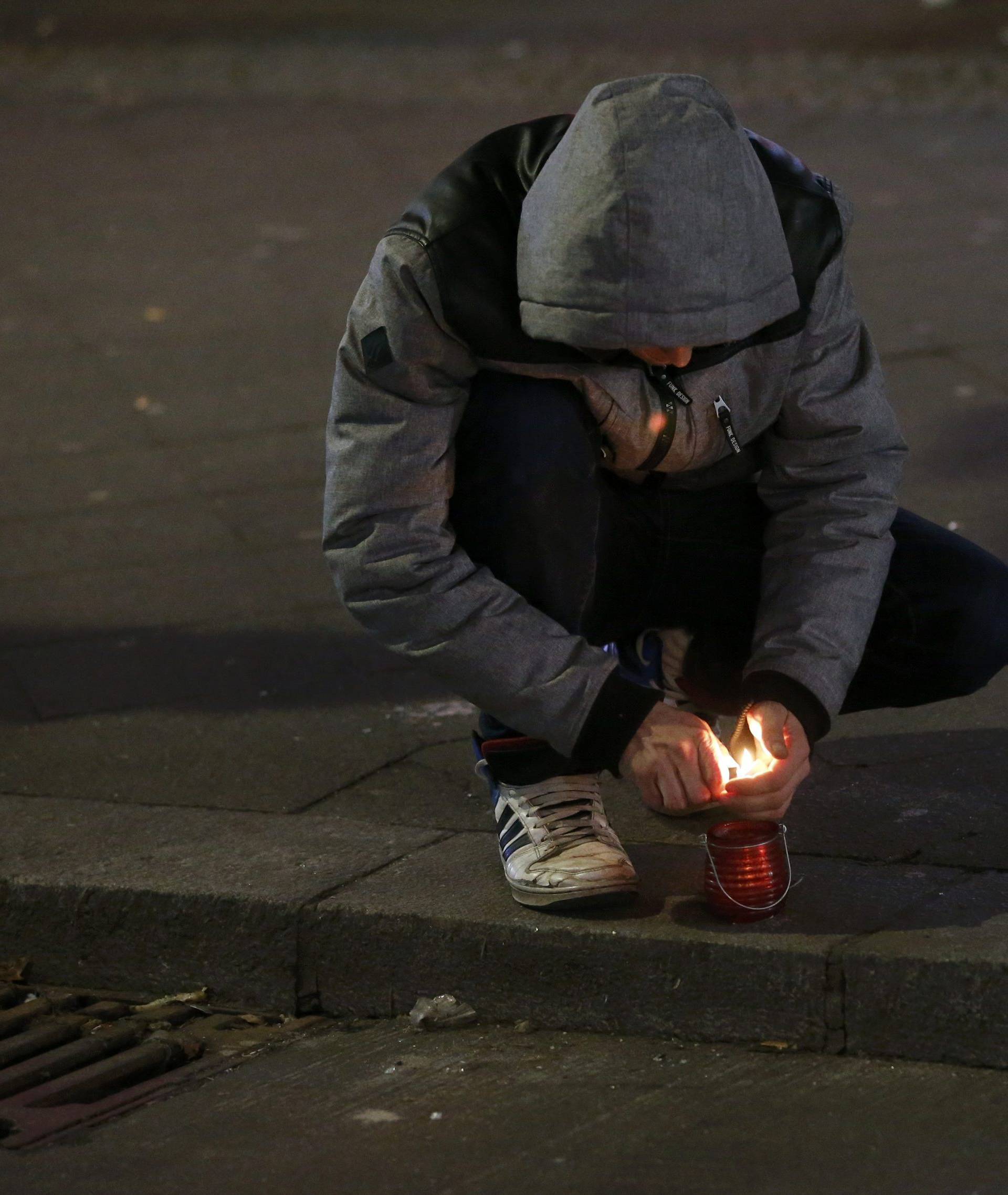A man lights a candle near the site where a truck ploughed through a crowd at a Berlin Christmas market