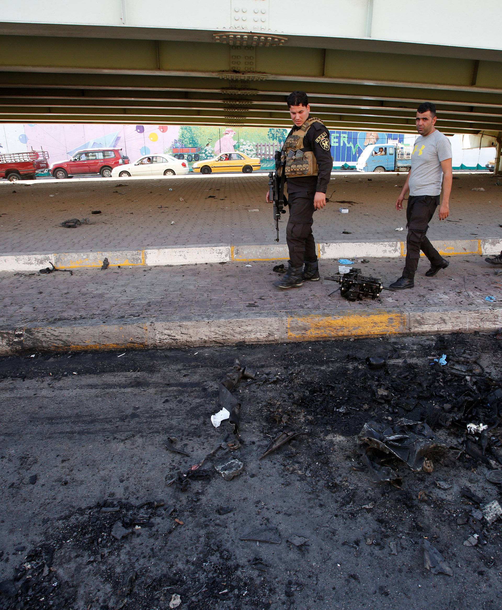 Members of Iraqi security forces walk past at the site of a suicide bomb attack at Nakheel Mall across from the oil ministry, in Baghdad