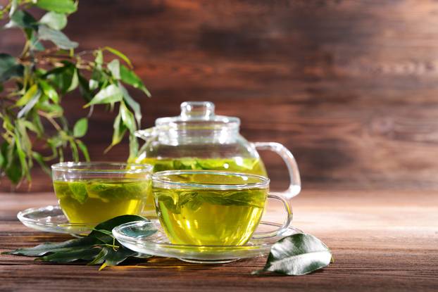 Cups of green tea on table on wooden background