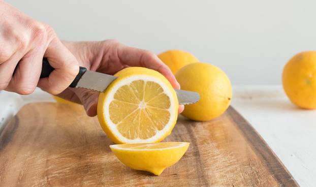 Middle aged woman's hands cutting lemons