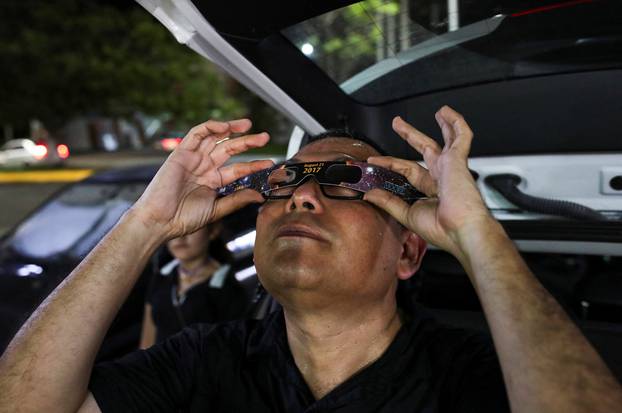 Astronomer Yuri Pena delivers special protective glasses to observe the solar eclipse to tourists and residents in Campeche