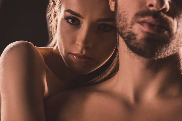 sensual lovers embracing and looking at camera, on brown
