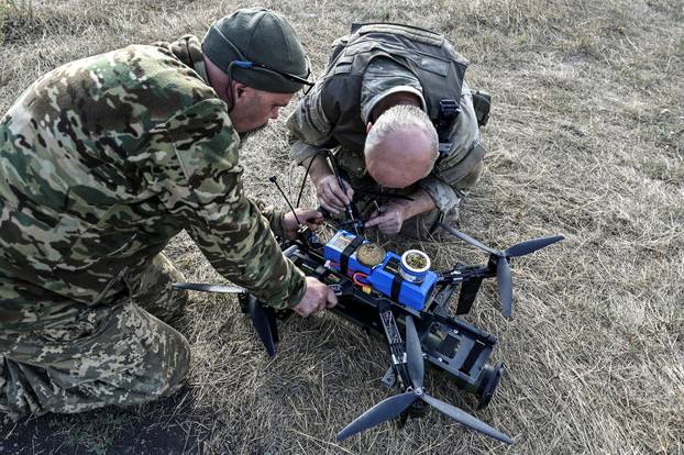 Ukrainian servicemen prepare for a test fly an FPV drone with an attached portable grenade launcher at their position near a frontline in the Zaporizhzhia region