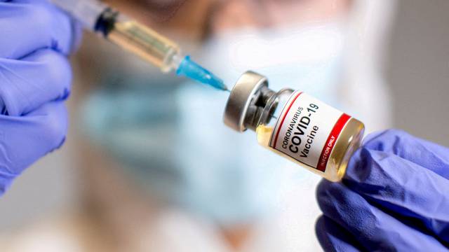 FILE PHOTO: A woman holds a medical syringe and a small bottle labelled "Coronavirus COVID-19 Vaccine