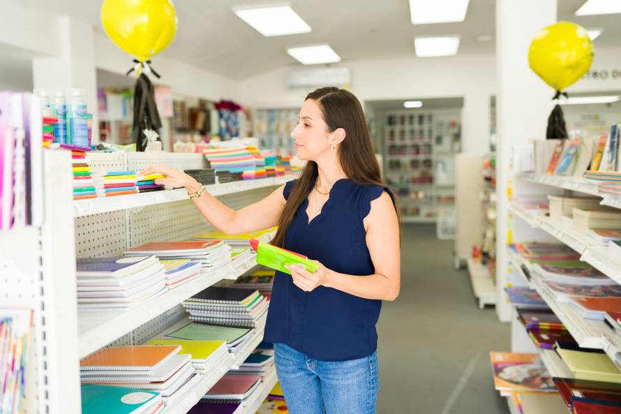 Woman,Browsing,Shelves,,Choosing,Colorful,Notebooks,And,Other,School,Supplies