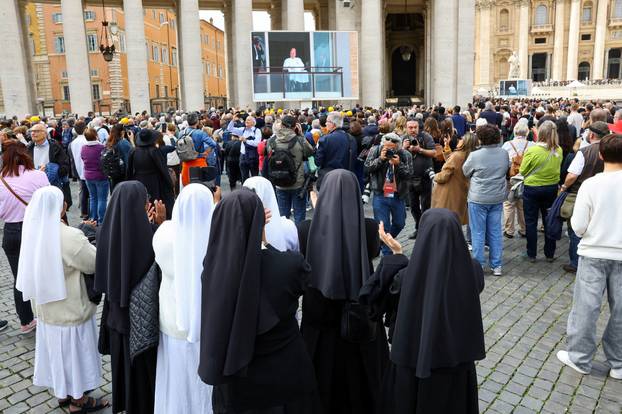 People watch Pope Francis makes first public appearance in five weeks, on a big screen in St. Peter's Square at the Vatican