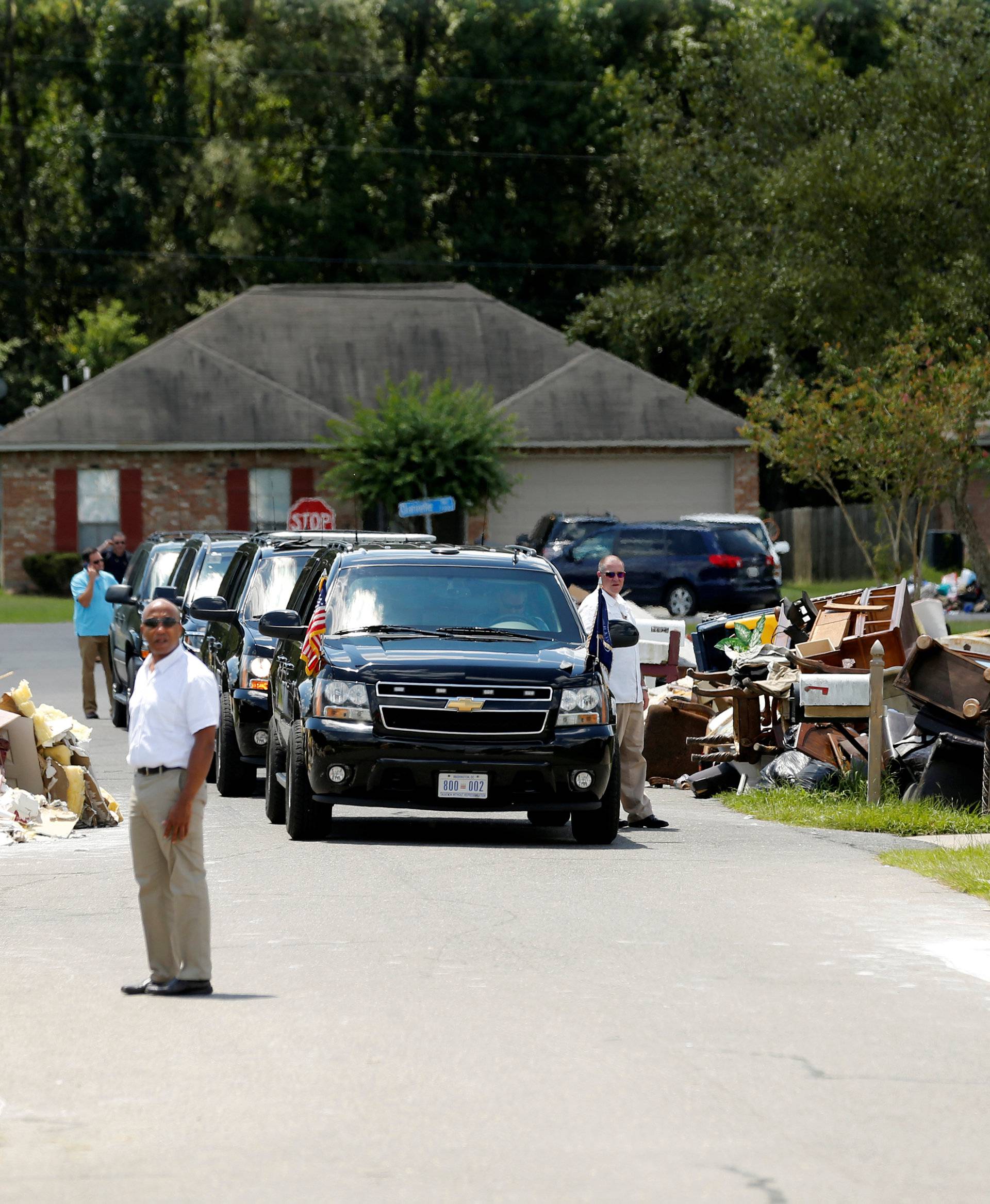 U.S. President Barack Obama's motorcade is seen nearby as he tours a flood-affected neighborhood in Zachary