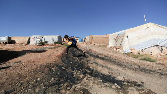 A boy jumps over sewage at a camp for internally displaced Syrians, in northern rebel-held Idlib