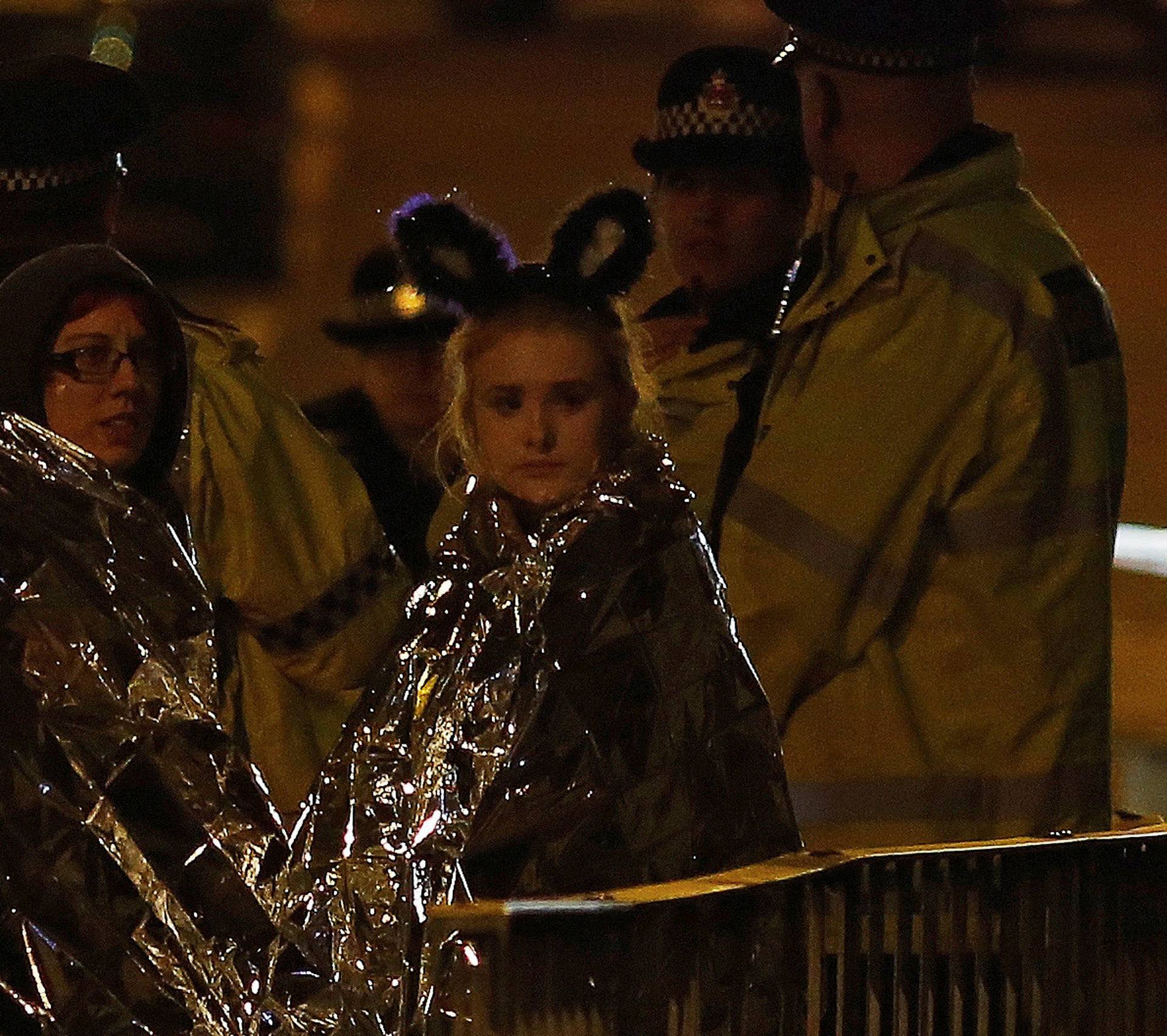 Two women wrapped in thermal blankets look on near the Manchester Arena, where U.S. singer Ariana Grande had been performing, in Manchester, northern England, Britain