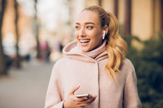 Stylish woman listening music on her airpods in city