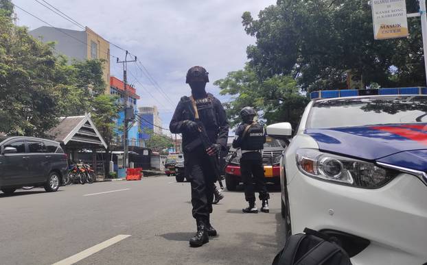 Armed police officers stand guard along a closed road following an explosion outside a Catholic church in Makassar, Indonesia